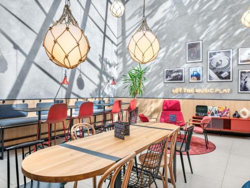 a restaurant with wooden tables and chairs and a wall at Ibis Budapest Centrum in Budapest