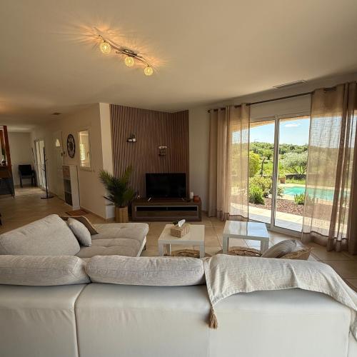 a living room with two white couches and a television at Villa Énalia in Barjac