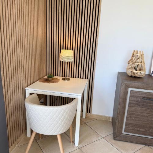 a white table with a chair and a lamp at Villa Énalia in Barjac