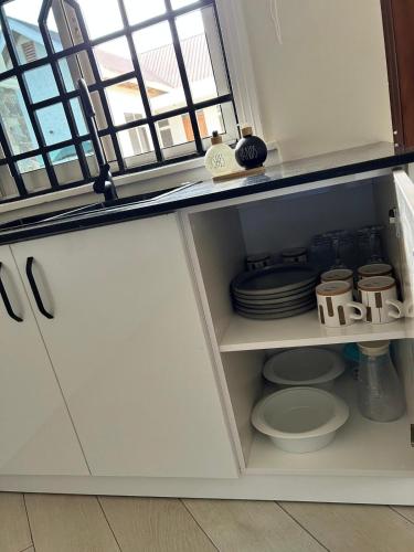 a cupboard with plates and dishes in a kitchen at Hazina Homes in Boma la Ngombe