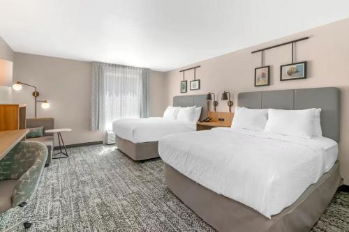 a hotel room with two beds and a desk at Sleep Inn & Suites Pensacola - University Area in Pensacola