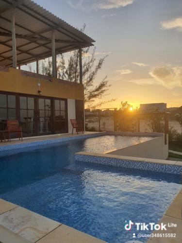 a swimming pool in front of a house with the sunset at Villa Maze Suites - Canoa Quebrada in Aracati