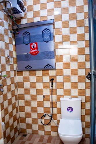 a bathroom with a toilet and a wall with tiles at Ramlat Service Apartment in Ilorin