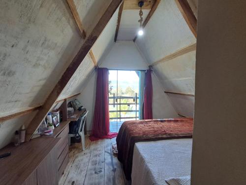a attic room with a bed and a window at Chalé bom jardim in Ibicoara