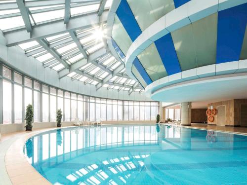 a large swimming pool in a building with a ceiling at Novotel Atlantis Shanghai in Shanghai