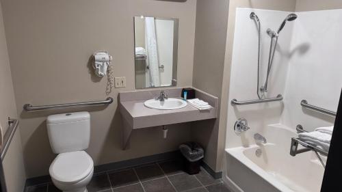 a bathroom with a toilet and a sink and a tub at Northwoods Inn and Suites in Ely