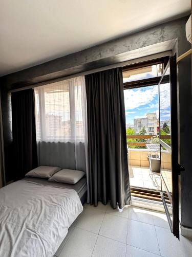 a bedroom with a bed and a large window at Central Point Apartment in Bar