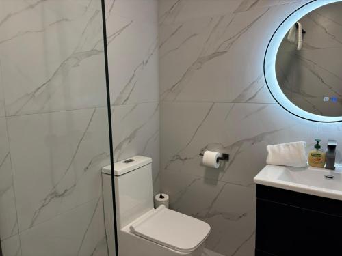 a white bathroom with a toilet and a mirror at Creevy Cove cottage in Kildoney