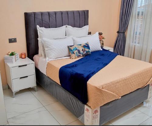 a bedroom with a large bed with a blue blanket at Mirai Apartments in Harare