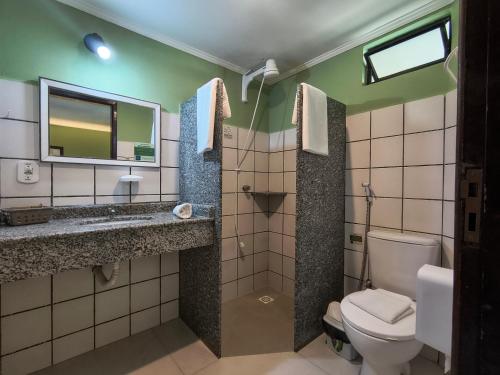a bathroom with a toilet and a sink and a mirror at Hotel Coco Beach in Conde