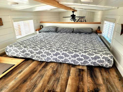 a large bed in a bedroom with wooden floors at Zion Couples Retreat Romantic Desert Tiny Home in Apple Valley