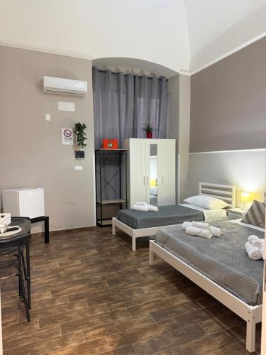 a room with two beds and a table in it at Dimora Leonida in Taranto