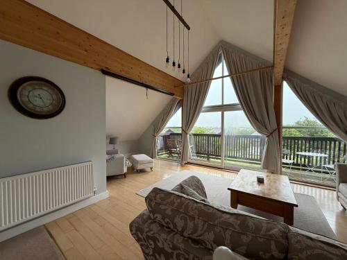 a living room with a couch and a large window at Lake View Lodge in Saint Columb Major