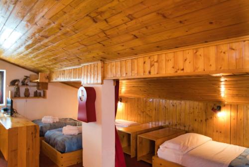 two beds in a room with wooden walls at Pian delle Betulle Alpine Loft in Margno