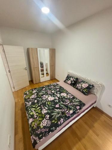a small bedroom with a bed with a floral blanket at Kapije Uba 51 in Ub