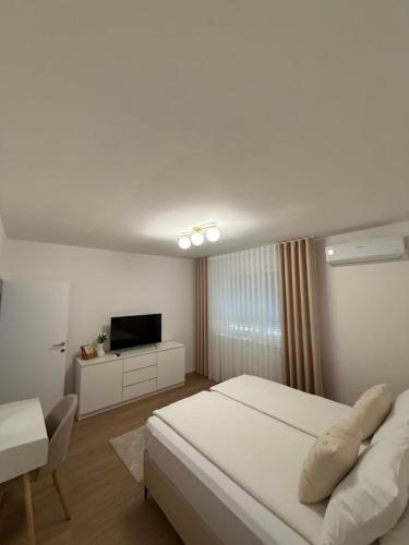 a white bedroom with a bed and a television at A&L Luxury Apartment in Tuzla
