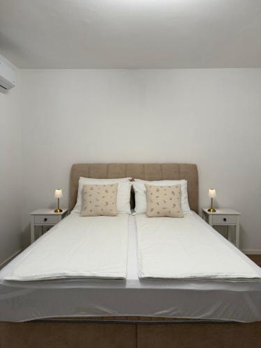 a large bed with white sheets and pillows at A&L Luxury Apartment in Tuzla