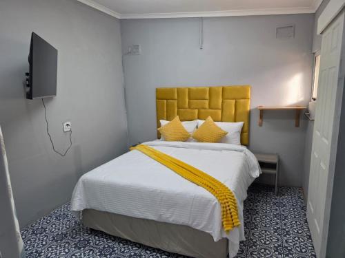 a bedroom with a large bed with a yellow headboard at Peaceful Accommodation in Durban
