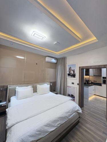 a bedroom with a large bed with white sheets at Maydec Plus Homes & Apartments in Abuja