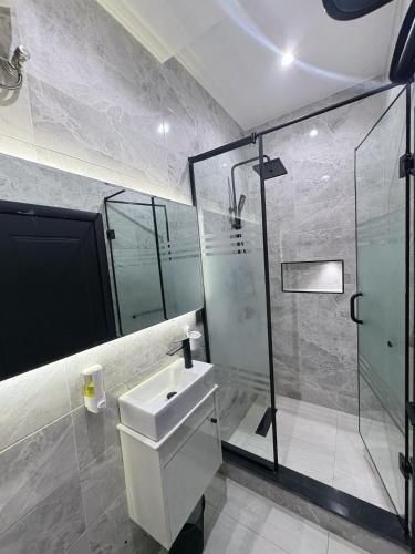 a bathroom with a sink and a glass shower at Maydec Plus Homes & Apartments in Abuja