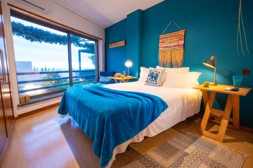 a bedroom with a bed with a blue wall at epicenter LAGOA in Lagoa