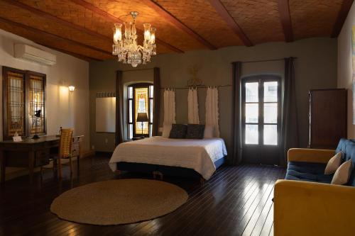 ein Schlafzimmer mit einem Bett, einem Tisch und einem Kronleuchter in der Unterkunft Hotel Villa 1927 in Chapala