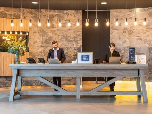 two people sitting at a large table with laptops at Novotel Edinburgh Centre in Edinburgh