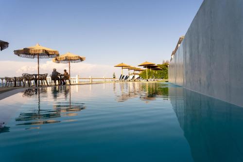 a pool of water with umbrellas and people sitting around it at Argassi Beach Hotel - Adults Only in Argassi