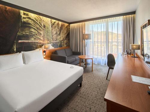 a hotel room with a large bed and a desk at Mercure Karpacz Skalny in Karpacz