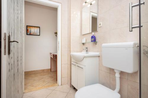 a white bathroom with a toilet and a sink at Apartment Bogomir in Podgora