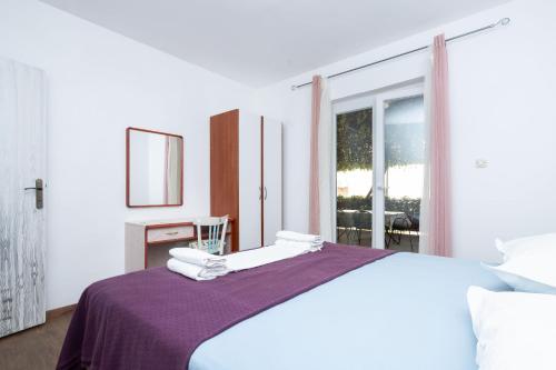 a bedroom with a bed with a purple blanket at Apartment Bogomir in Podgora