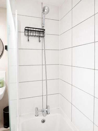 a shower in a white tiled bathroom with a shower head at Delwin Place - Quiet Stay & Sparkling Bathroom in Dunstable