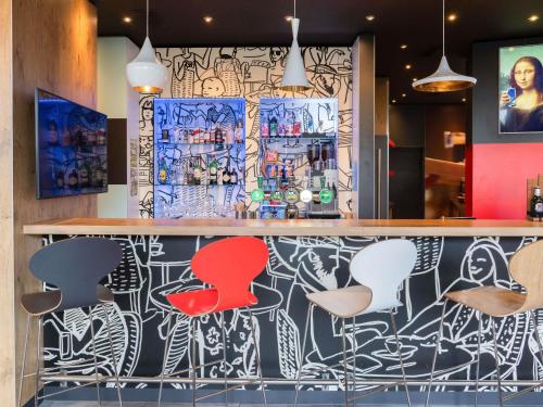 a bar with colorful stools in a restaurant at ibis Genève Aéroport in Geneva