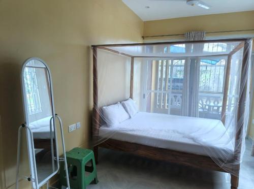 a bedroom with a canopy bed in front of a window at Harlequin Diani in Diani Beach