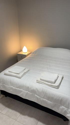 a bed with white sheets and towels on it at Departamento Los Ceibos 2 in San Fernando del Valle de Catamarca