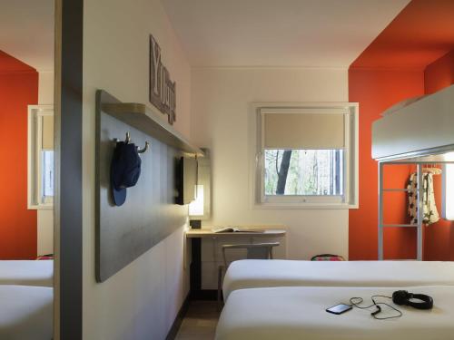 a hotel room with two beds and a desk at ibis budget Amsterdam Airport in Badhoevedorp