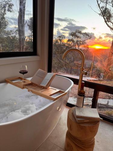 eine Badewanne mit einem Buch und einem Glas Wein in der Unterkunft Zenith Tiny Home in Montacute