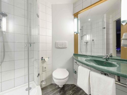 a bathroom with a sink and a toilet and a mirror at Hotel Ibis Bregenz in Bregenz