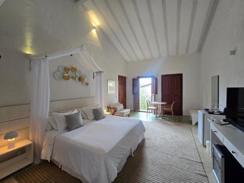 a bedroom with a white bed and a television at Divina Pousada in Pirenópolis