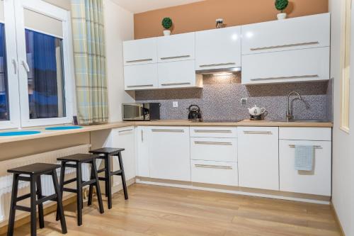 a kitchen with white cabinets and black stools at Apartament Wygodny in Ustrzyki Dolne