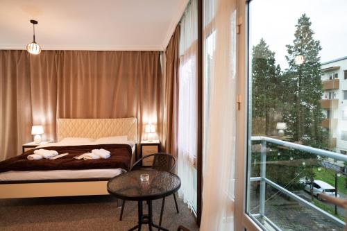a bedroom with a bed and a table and a balcony at Chill Out Hotel Tskaltubo in Tsqaltubo