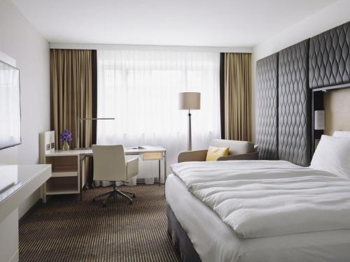 a hotel room with a bed and a desk at PULLMAN Berlin Schweizerhof - City Center, Zoo und Kurfürstendamm in Berlin