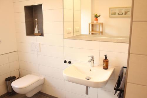 a white bathroom with a sink and a toilet at Ferienwohnung "Groote Koje" in Barßel