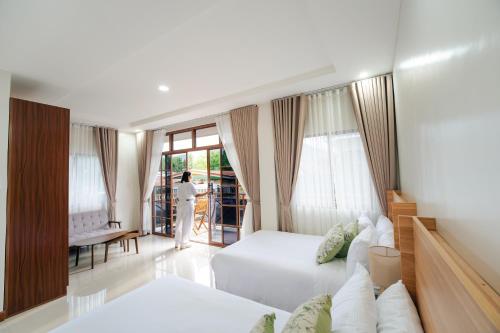 a living room with two beds and a woman standing in the window at Casa Lucia Resort Hotel in Oslob