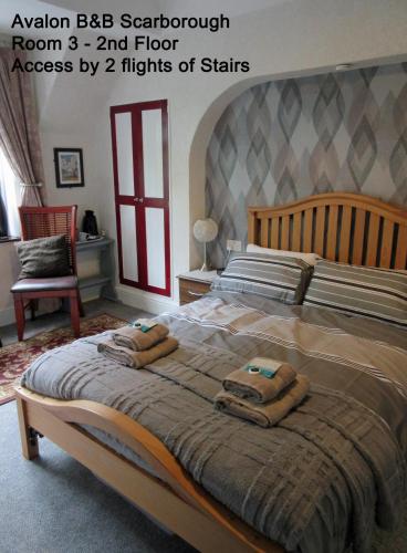 a bedroom with a large bed with towels on it at Avalon B&B Scarborough in Scarborough
