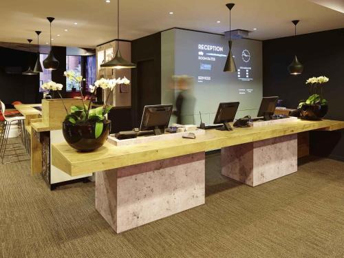 a lobby with a desk with laptops on it at ibis Reading Centre in Reading