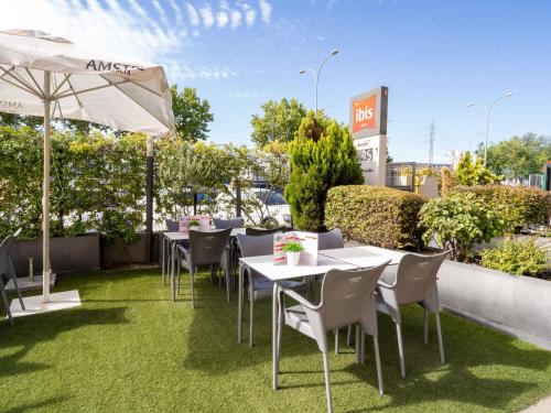 a row of tables and chairs with an umbrella at Ibis Madrid Alcorcon Tresaguas in Alcorcón