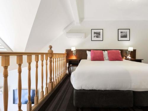 a bedroom with a large bed and a staircase at Mercure Canberra in Canberra