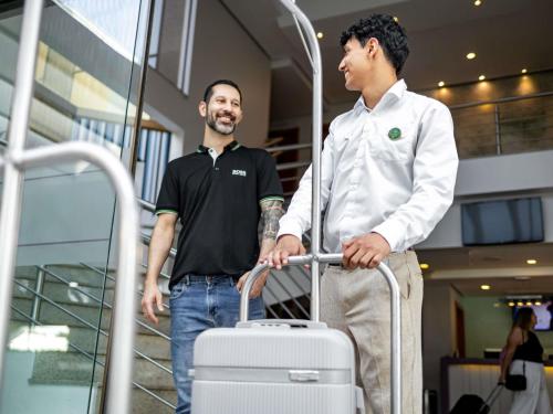 two men standing in an airport with a suitcase at Mercure Florianópolis in Florianópolis