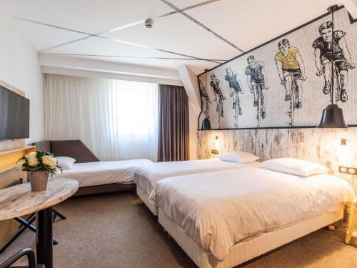 a hotel room with two beds and a tv at ibis Styles Dinan Centre Ville in Dinan